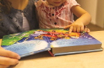 ▶ 크리스티나와 딸이 이야기 책을 읽고 있는 모습(출처: 월드와치모니터)